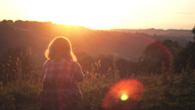 ein Mädchen, das den Sonnenuntergang beobachtet